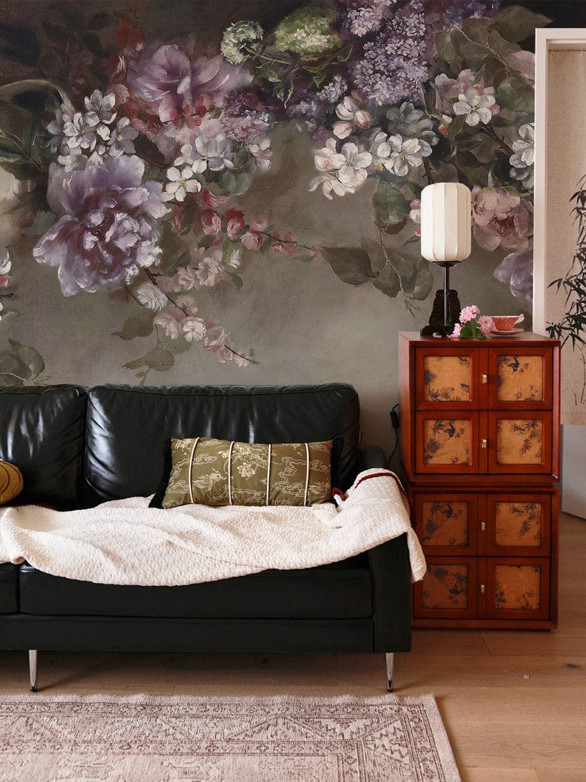 Vintage floral mural wallpaper with a green and purple bloom design behind a black sofa and cabinet.