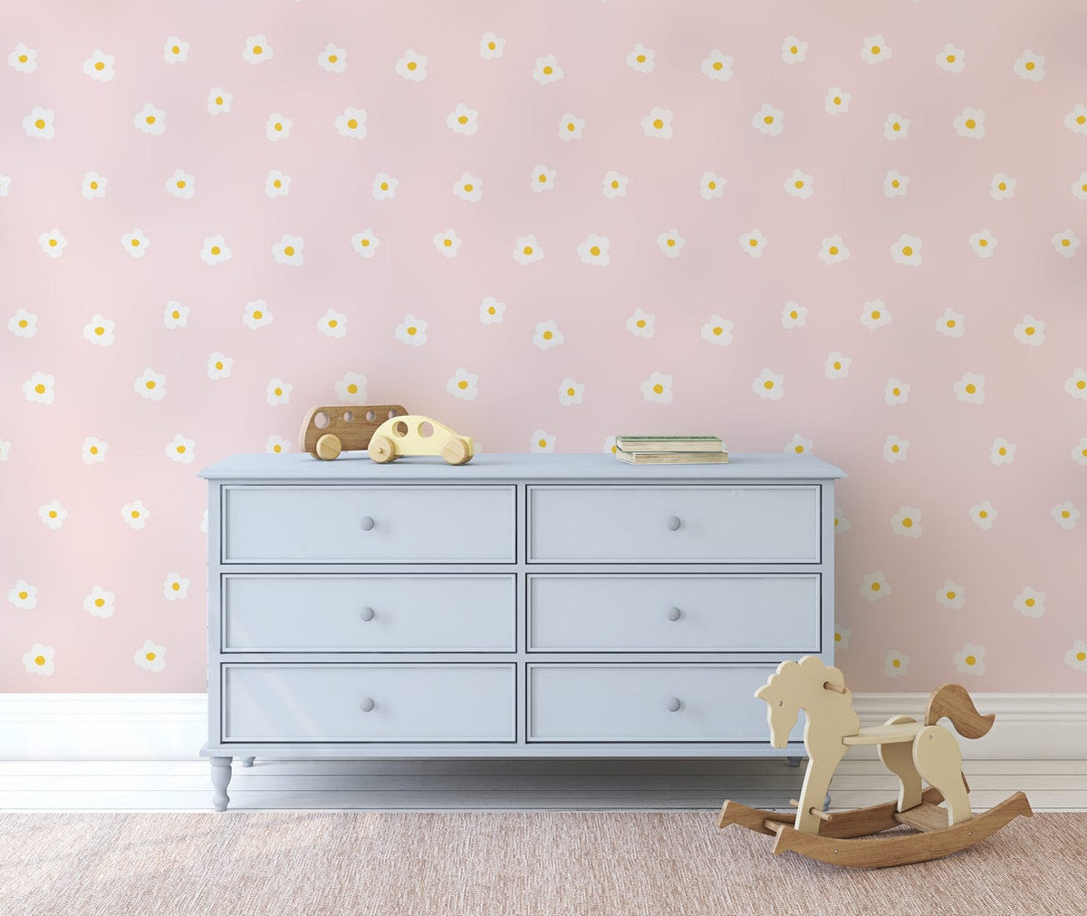 Pastel pink floral wallpaper with daisies, blue dresser, wooden rocking horse, and beige carpet.
