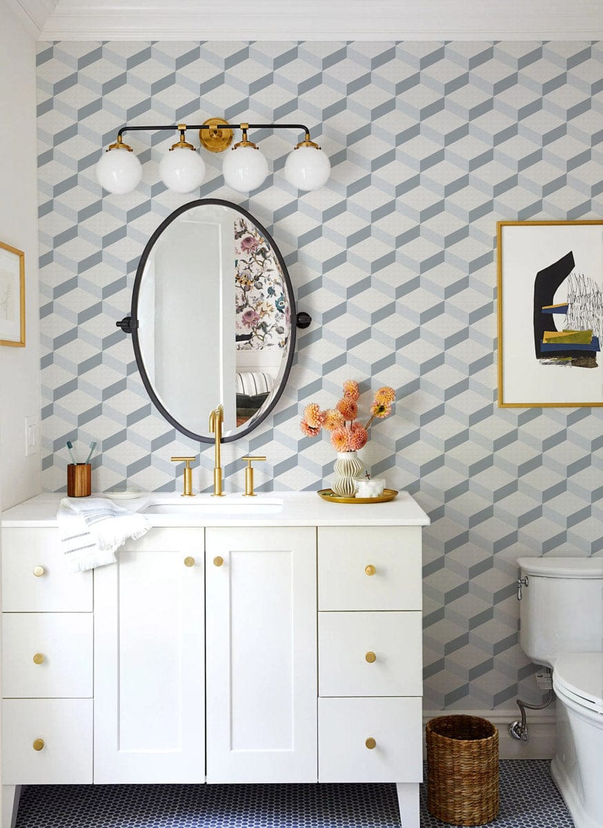 Modern geometric grey-white wallpaper in bathroom with white vanity, round mirror, and gold accents.