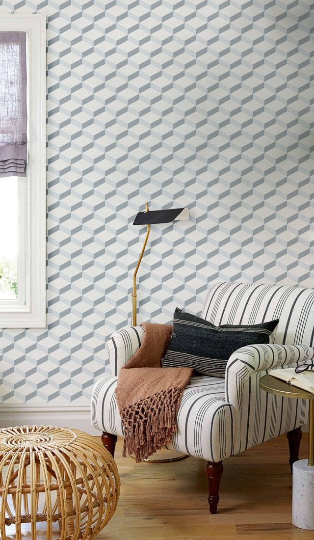 Modern geometric wallpaper with striped armchair, wood flooring, and stylish lamp in elegant living room.