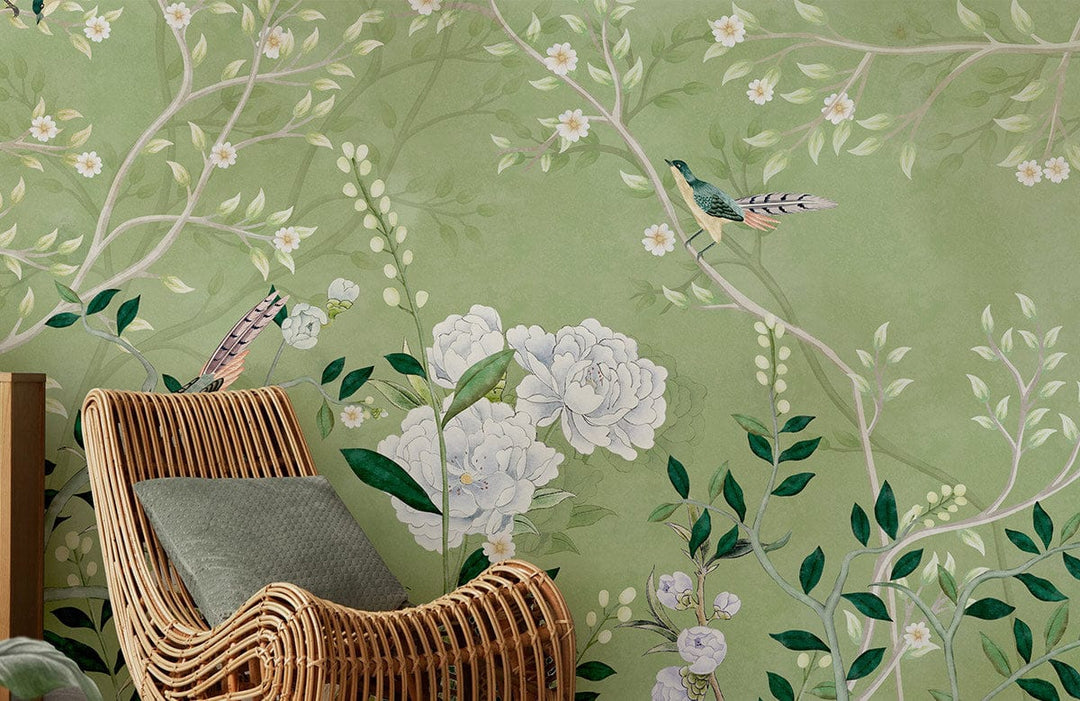 Elegant green floral wallpaper with birds behind rattan chair in nature-themed living room.