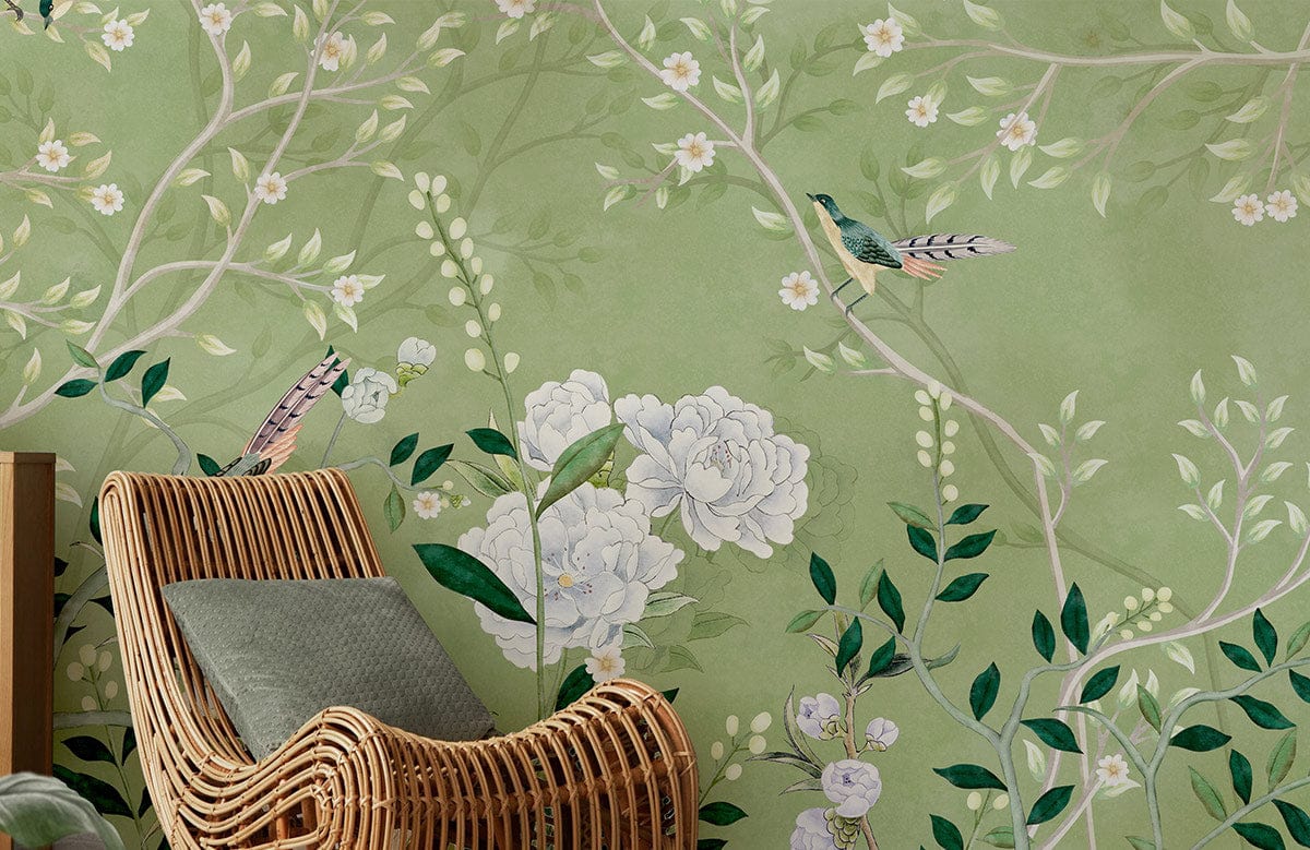 Elegant green floral wallpaper with birds behind rattan chair in nature-themed living room.