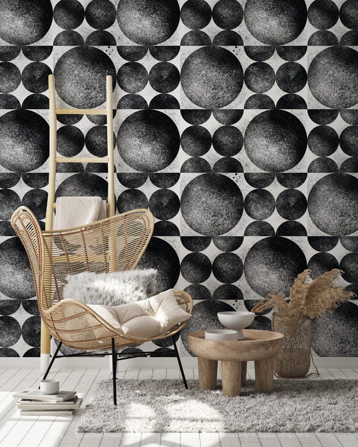 Monochrome geometric spheres wallpaper in modern room with wicker chair, wooden ladder, and soft rug.