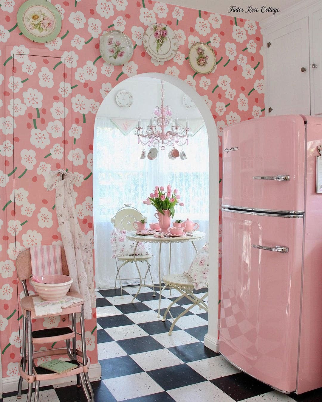 Romantic pink floral blossom wallpaper, vintage pink fridge, black-and-white checkered floor, elegant kitchen setting.