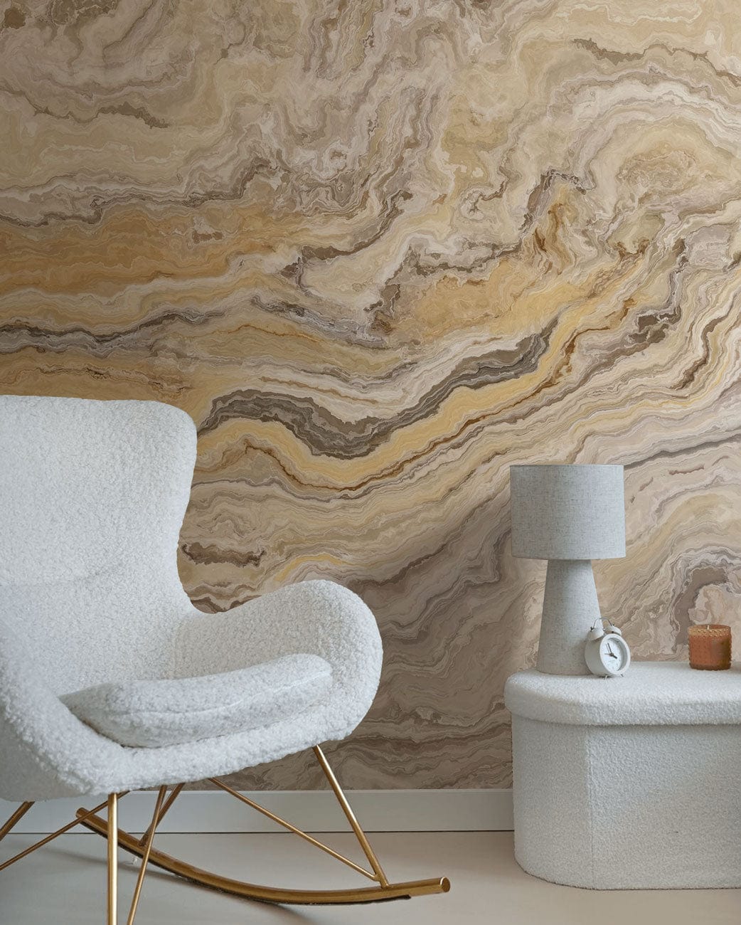 Elegant interiors with Marble Swirl Mural, cosy white armchair, textured lamp, beige stone table.