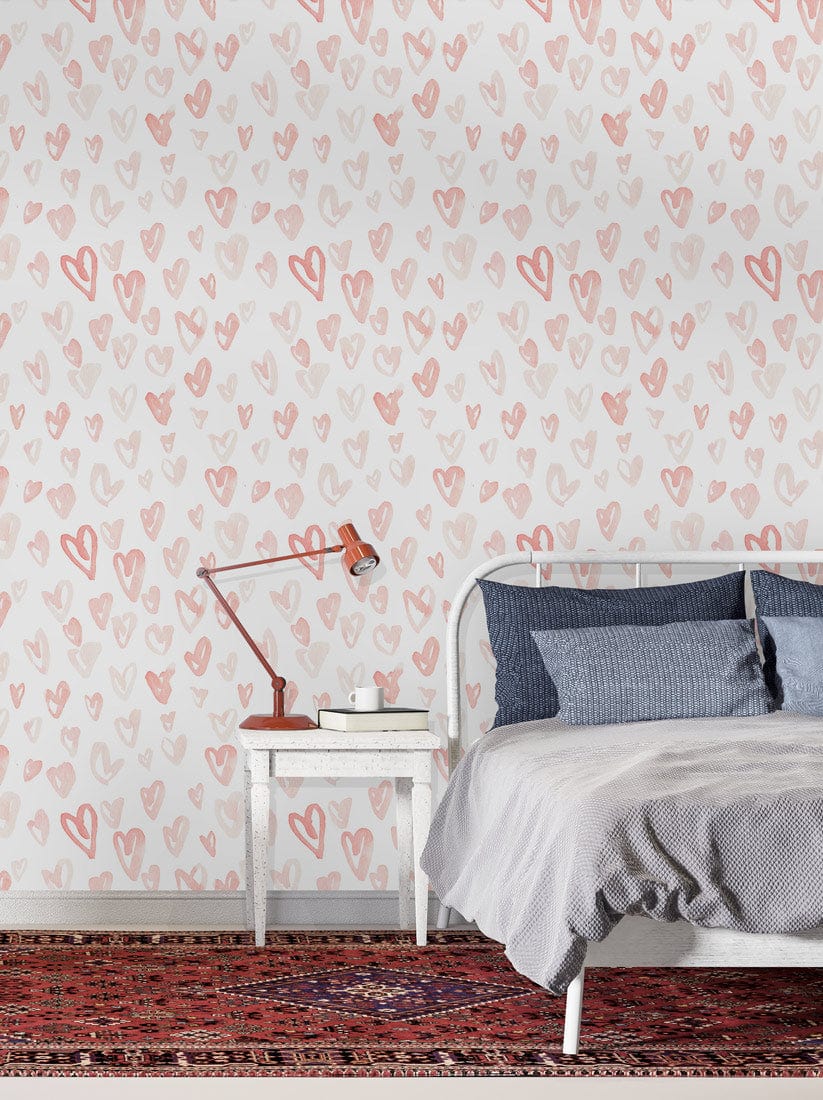 Charming pastel heart wallpaper in bedroom with metal bed, red rug, and vintage white side table.