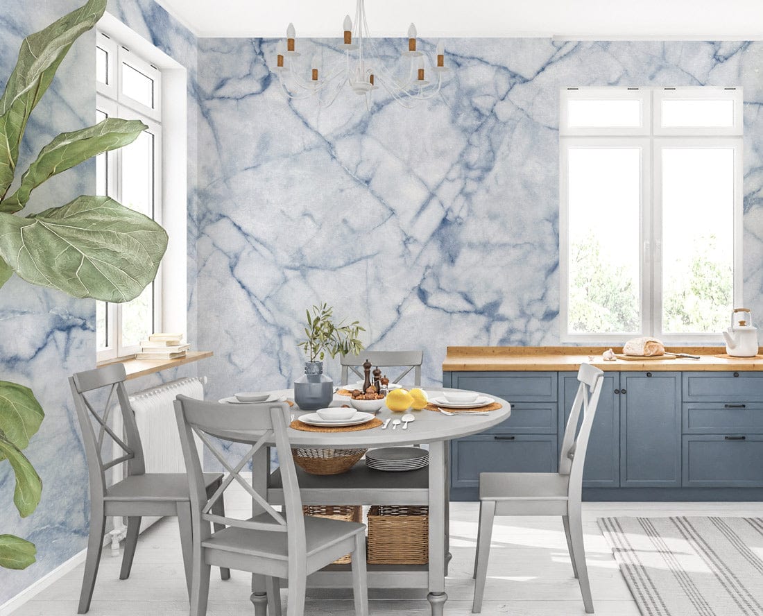 Elegant blue marble wallpaper in modern dining room, grey furniture, wooden countertop, striped rug, plant.