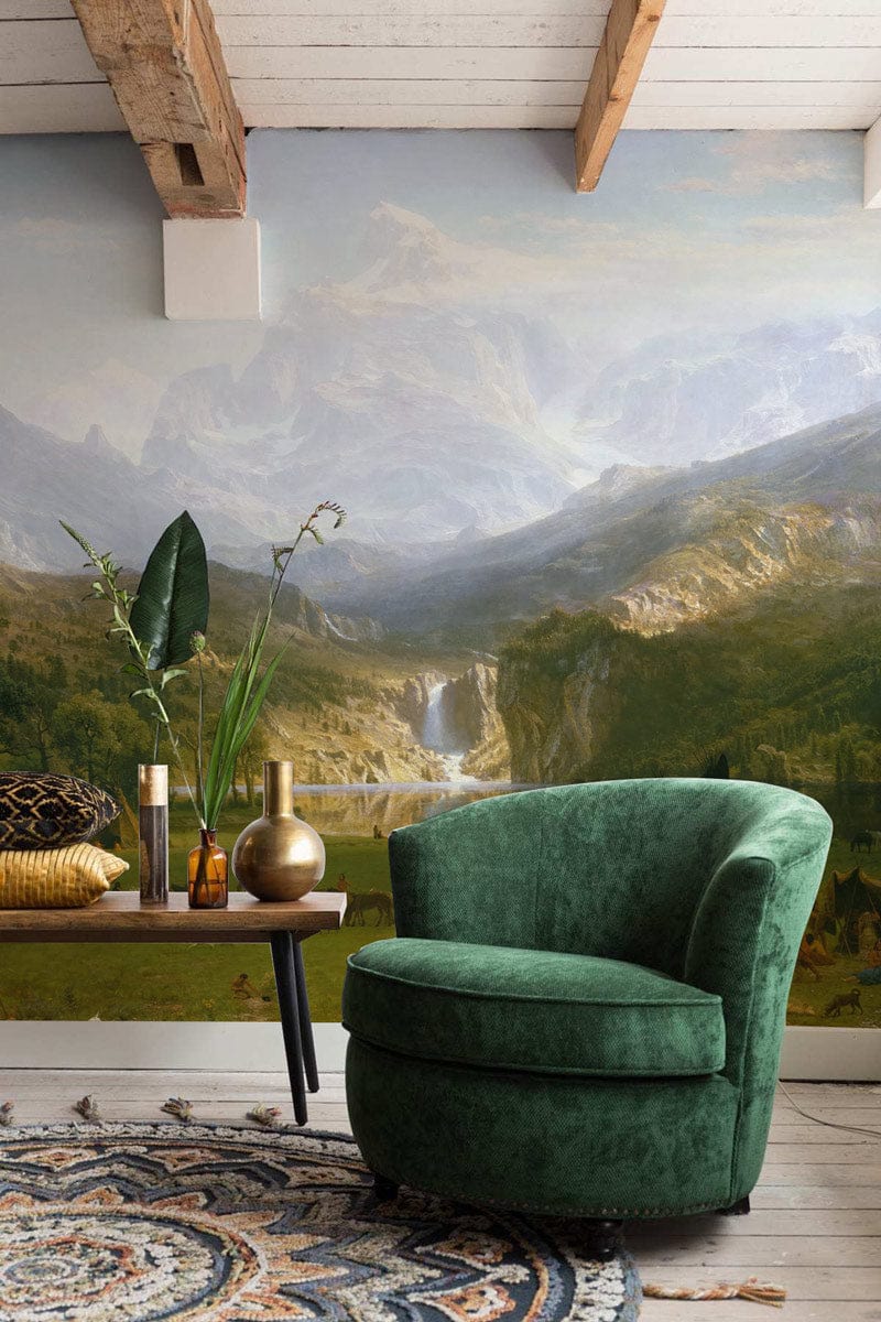Majestic Mountain Vista mural wallpaper, green armchair, rustic table, nature-themed room. Serene landscape decor.