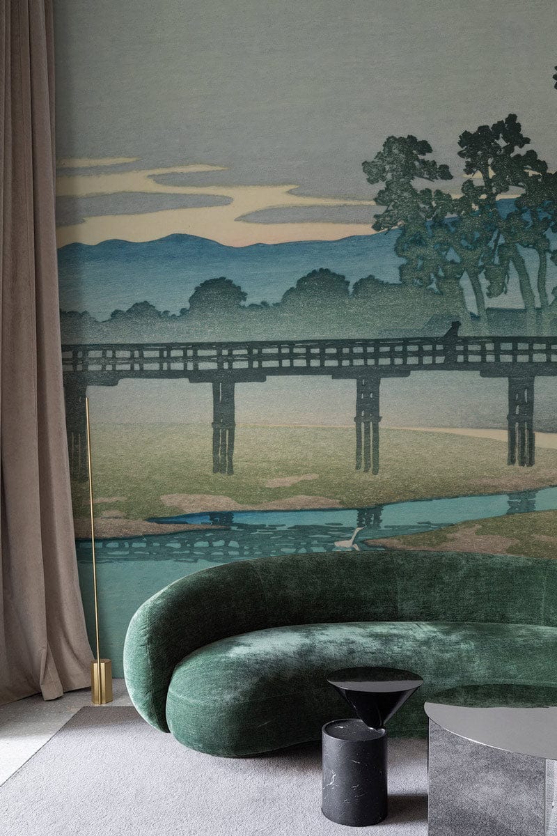Green curved sofa, grey carpet, elegant drapes, serene Japanese landscape mural with tranquil bridge design.