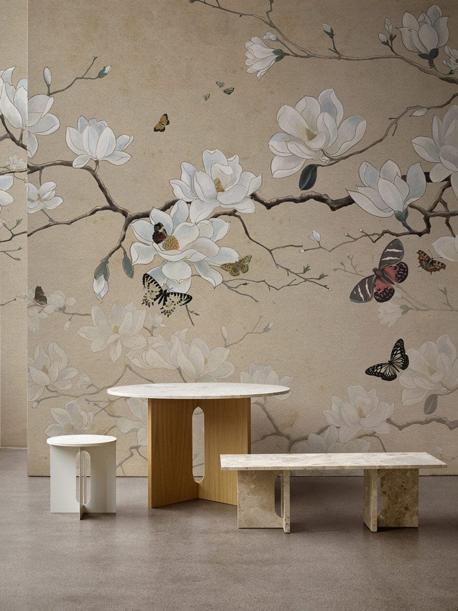 Elegant beige magnolia and butterfly floral mural wallpaper in tranquil room with minimalist wooden furniture.