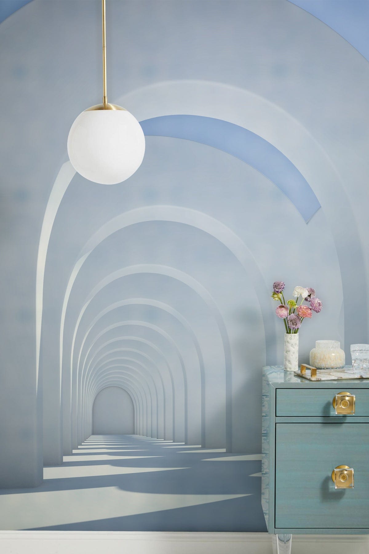 Elegant minimalist archway mural wallpaper, modern pendant light, blue sideboard, and white flooring in room.