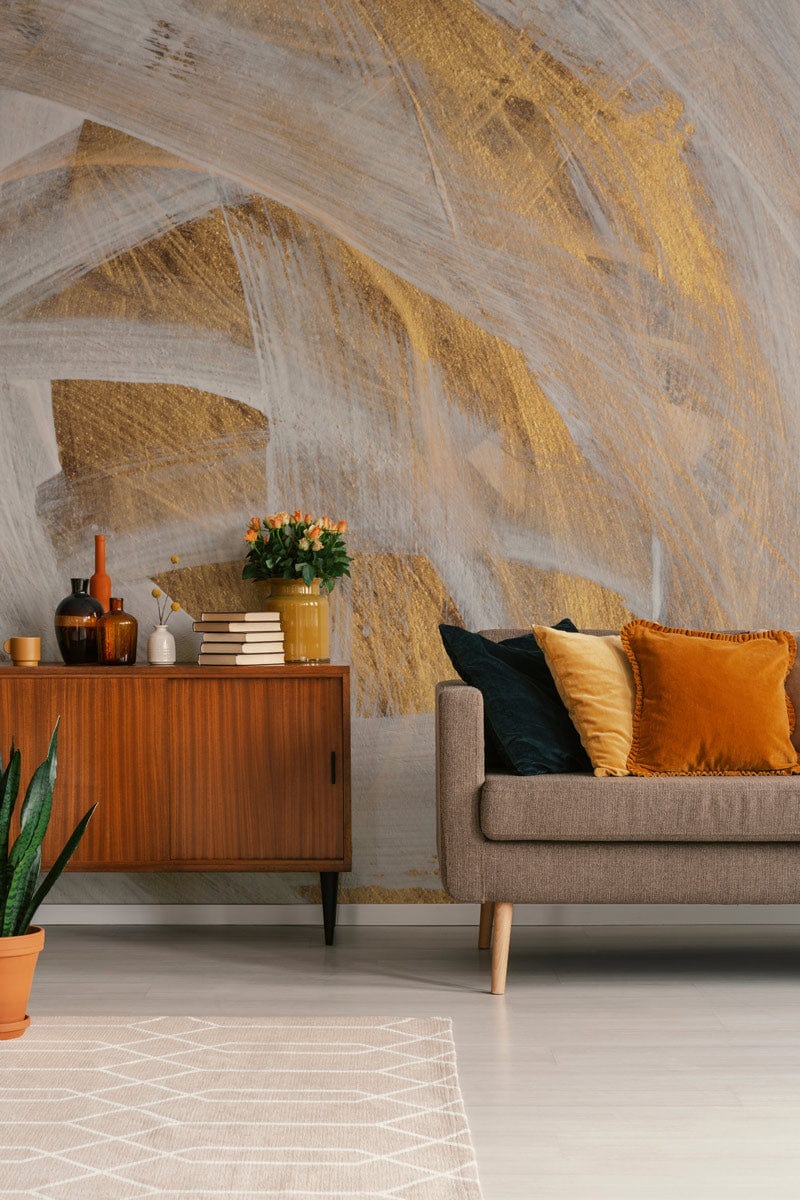 Elegant mural wallpaper features gold and white brushstrokes with mid-century sideboard, grey sofa, light flooring.