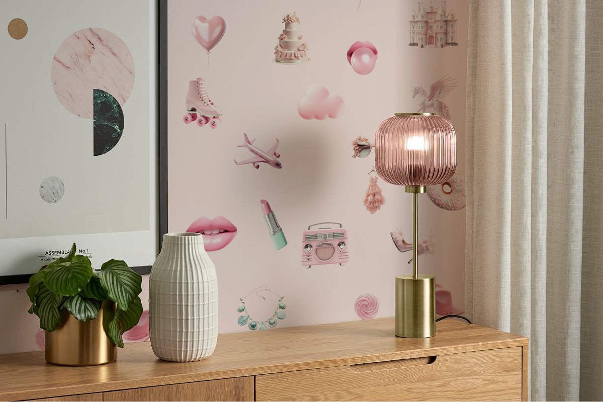 Chic vintage pink patterned wallpaper, pastel accents, wooden sideboard, pink lamp, and modern framed art.
