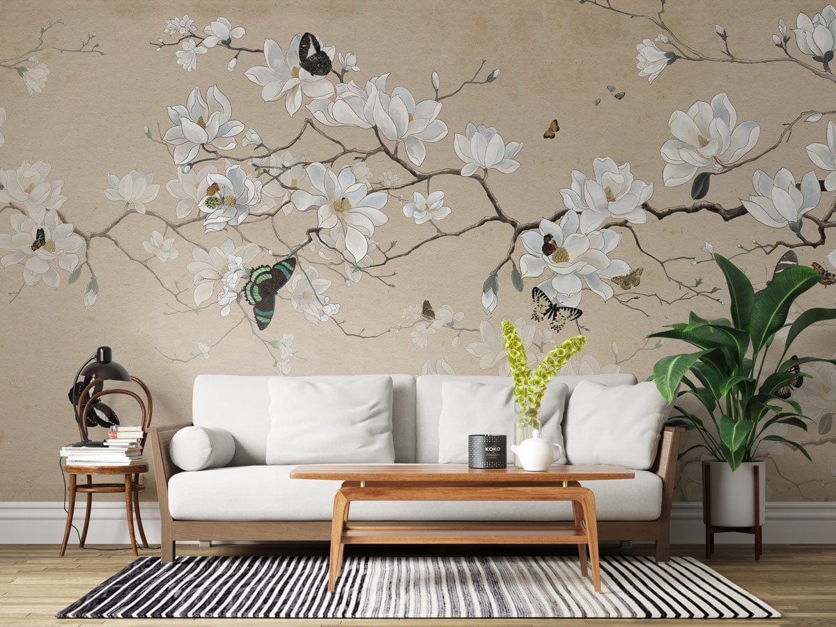 Elegant Beige Magnolia and Butterfly Mural Wallpaper with white sofa, wooden table, striped rug, and plants.