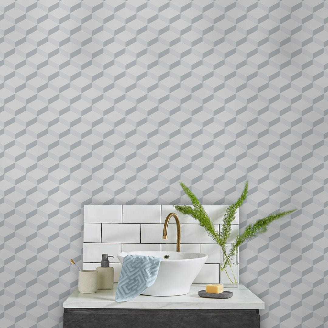 Modern geometric grey and white wallpaper in bathroom with white sink, gold tap, and tiled splashback.