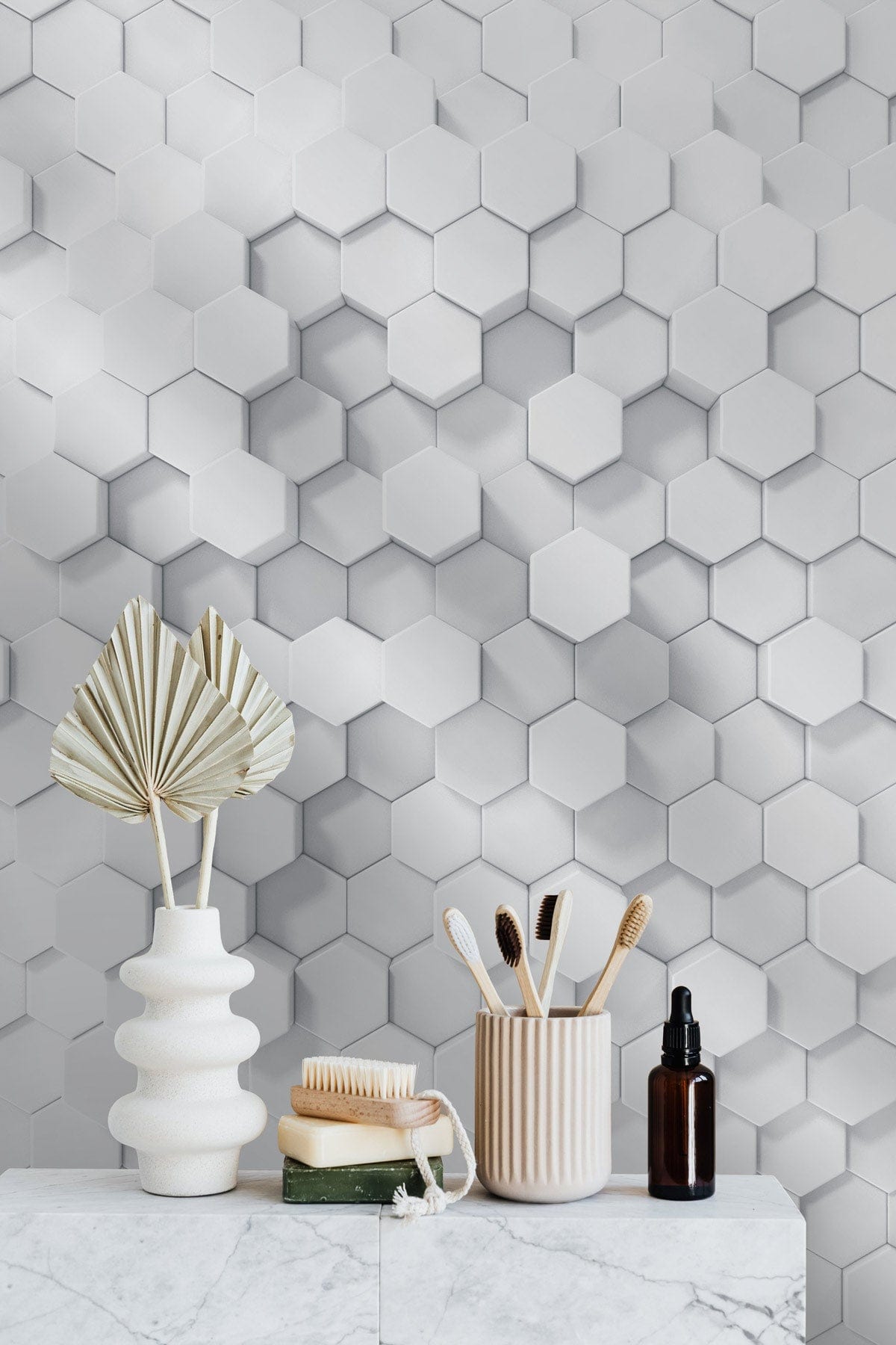 Geometric white hexagonal 3D wallpaper, minimalist design; vases and toiletries on marble countertop.