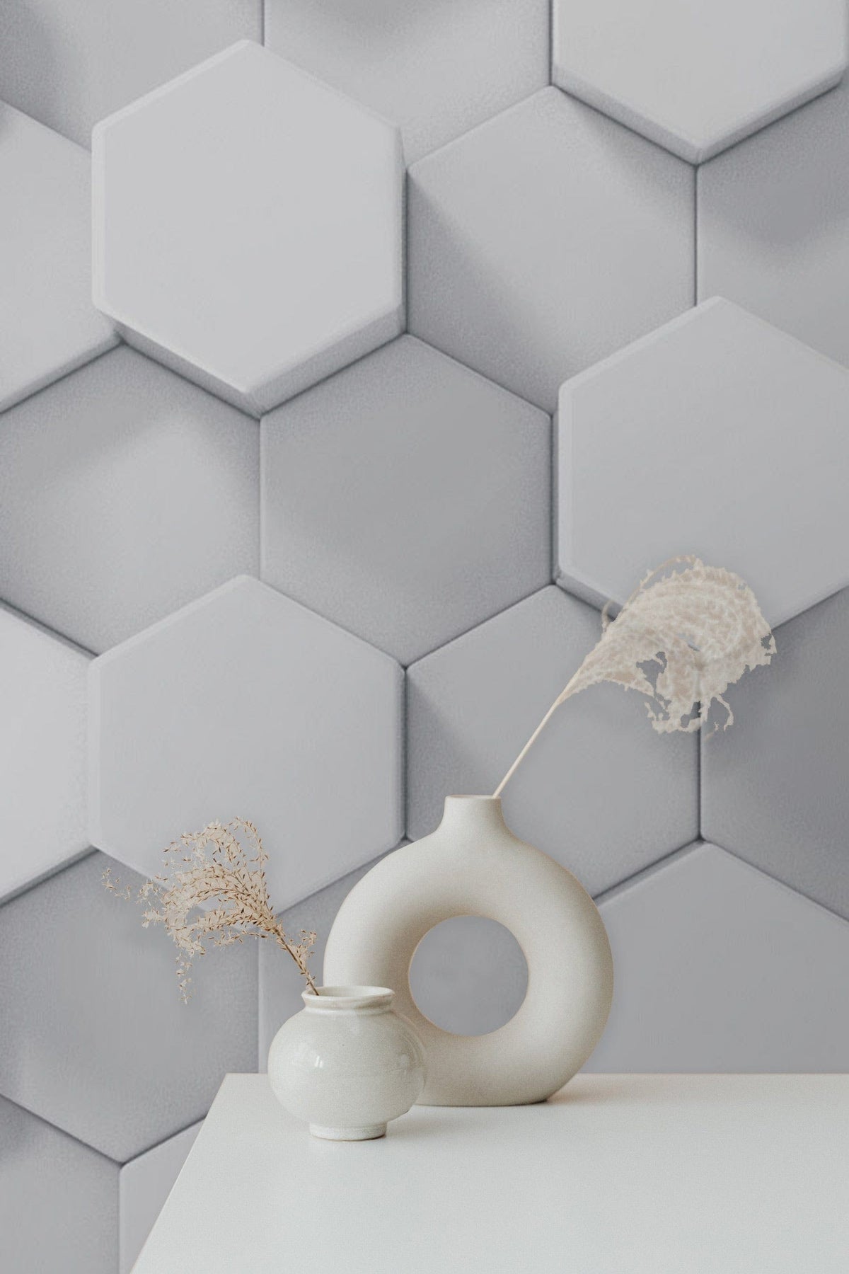 Geometric white hexagonal 3D wallpaper, minimalist design with decorative vases on a white table.