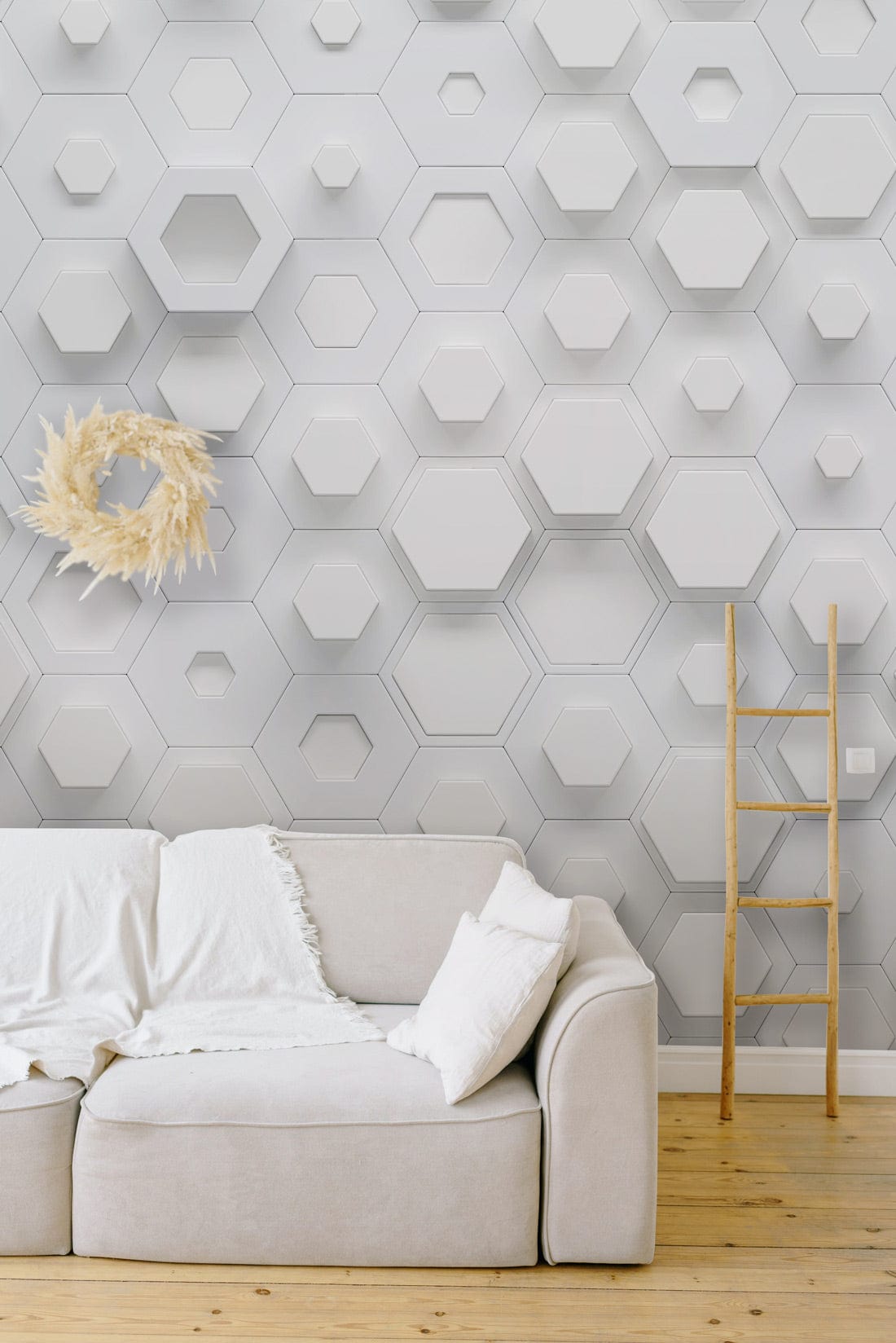 White hexagonal geometric wallpaper, modern 3D wall design, beige sofa, wooden ladder, light wood flooring.