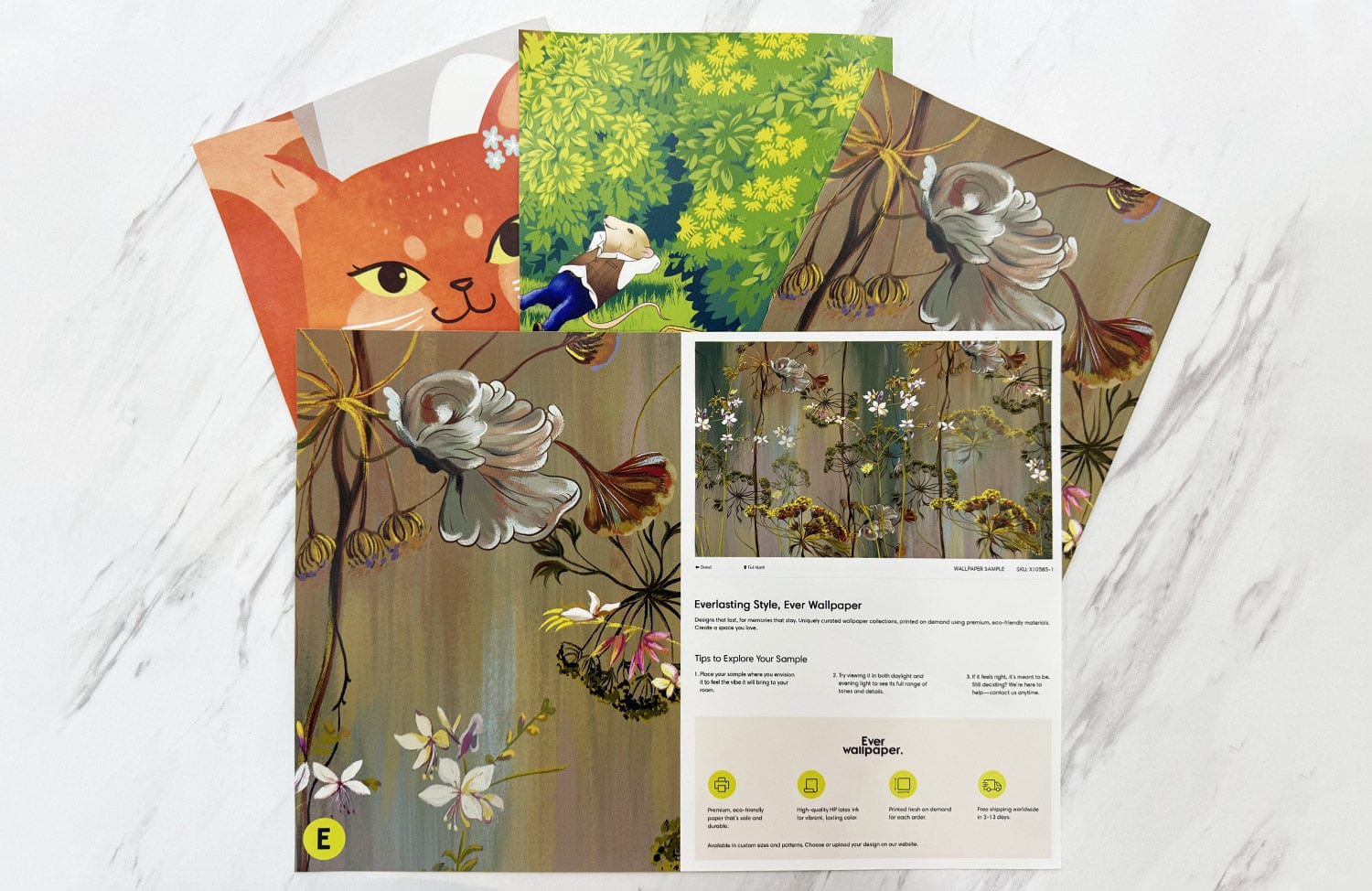 Whimsical mural wallpaper samples on marble surface; featuring nature, cosy cat design in vibrant colours.