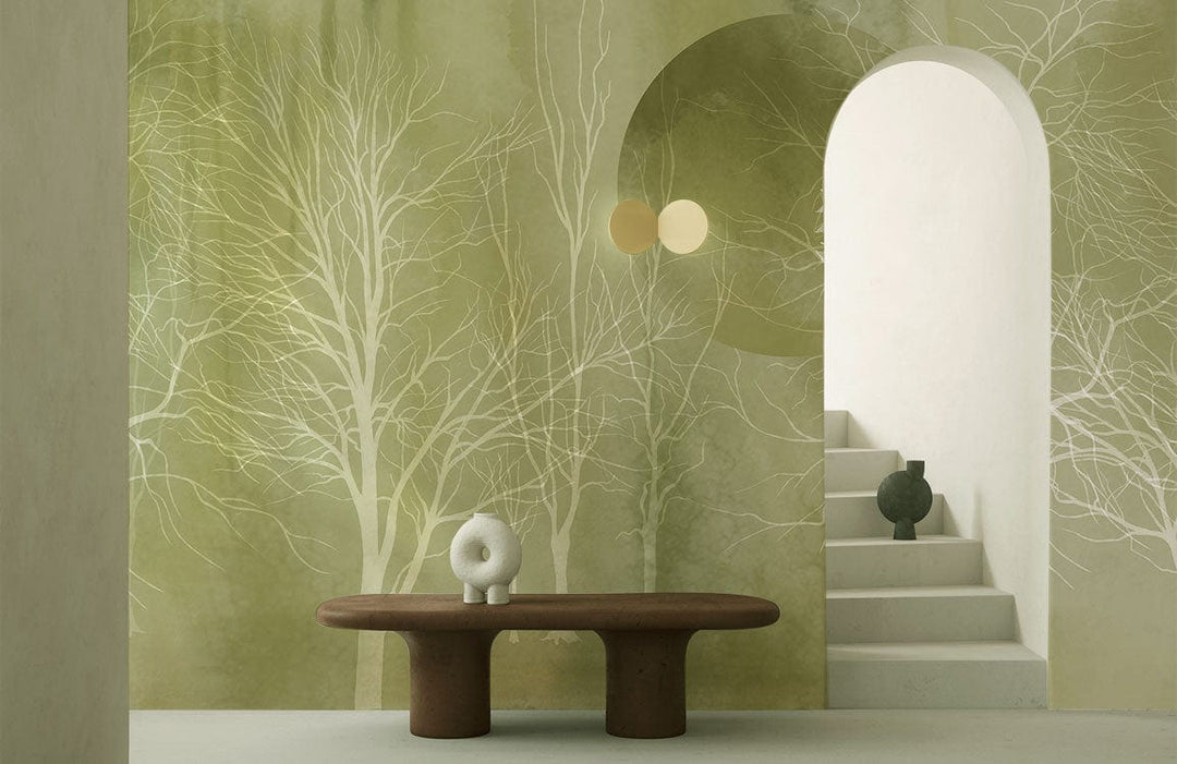 Enchanting Green Forest Mist Mural Wallpaper features ethereal trees, brown table, white staircase, arched doorway.
