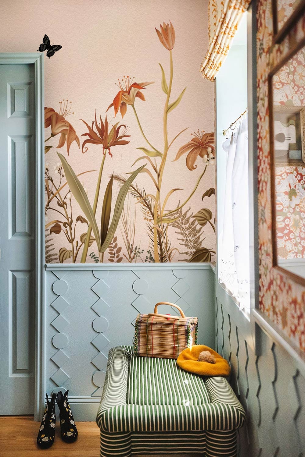 Vintage botanical mural wallpaper with earthy tones, butterflies; striped bench, light blue doors, hallway.