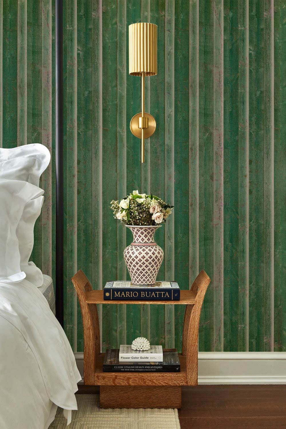 Vintage green striped marble wallpaper in bedroom with wooden nightstand and brass sconce lamp.
