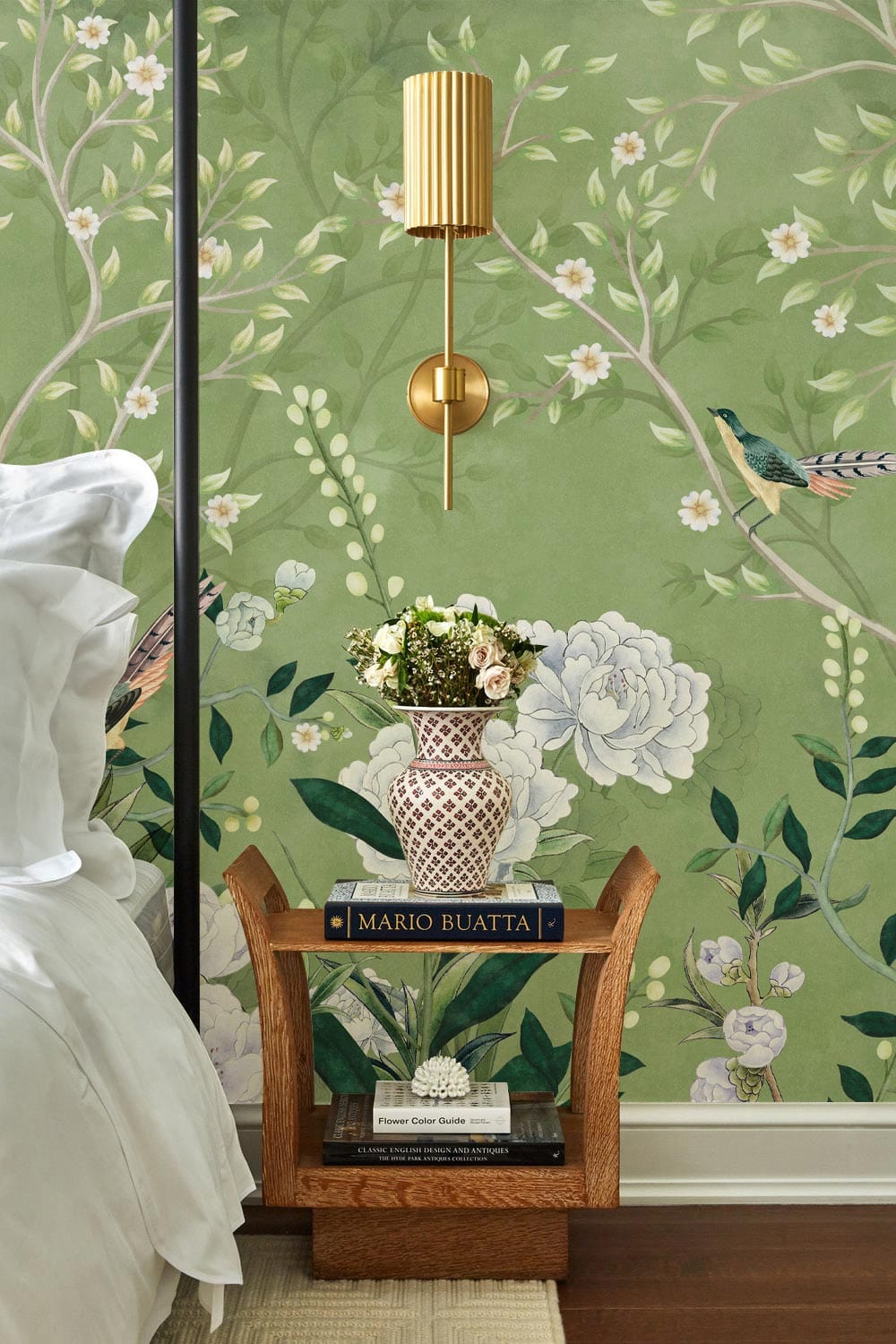 Elegant green floral wallpaper in bedroom, traditional design, brass light, wooden nightstand, white bedding.