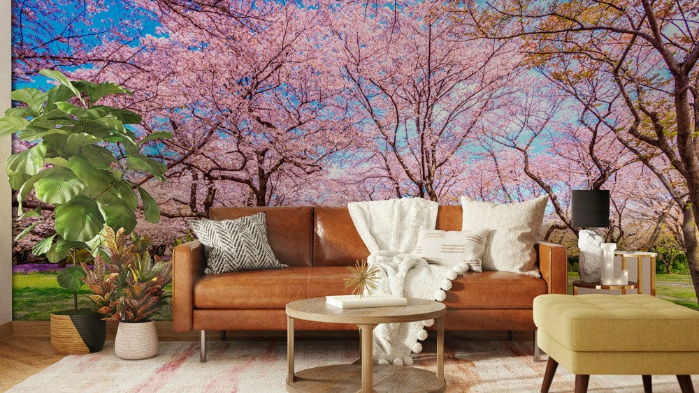 Blossoming Cherry Grove Wallpaper in living room with brown leather sofa, beige ottoman, wooden flooring.