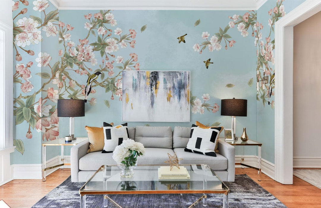 Tranquil Sky Blossom Mural Wallpaper in pastel tones featuring grey sofa, abstract art, wooden flooring.