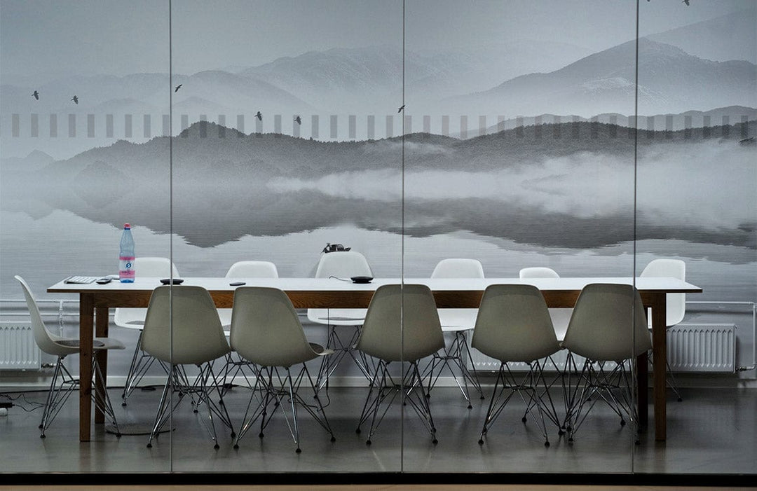 Tranquil Misty Mountains mural in conference room with white chairs, wooden table, grey flooring.
