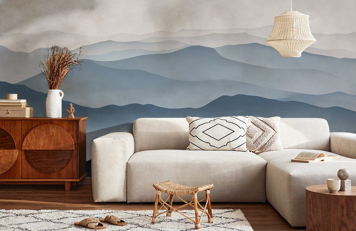 Elegant lounge with Serene Blue Grey Mountain Mist mural wallpaper, cream sofa, wicker pendant light, wooden sideboard.
