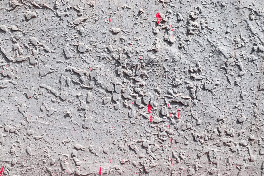 Rustic Textured Concrete Effect Wallpaper with Subtle Red Accents Design