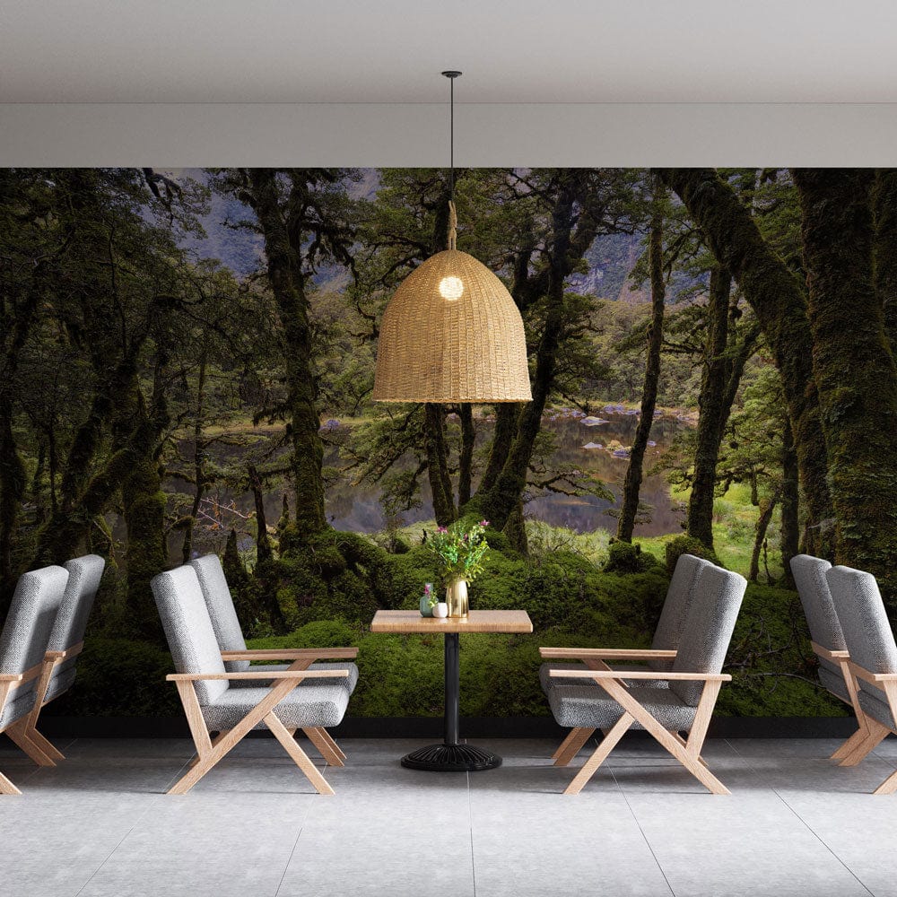 Enchanted Forest Green scenic mural wallpaper in dining room with modern grey chairs, pendant light.