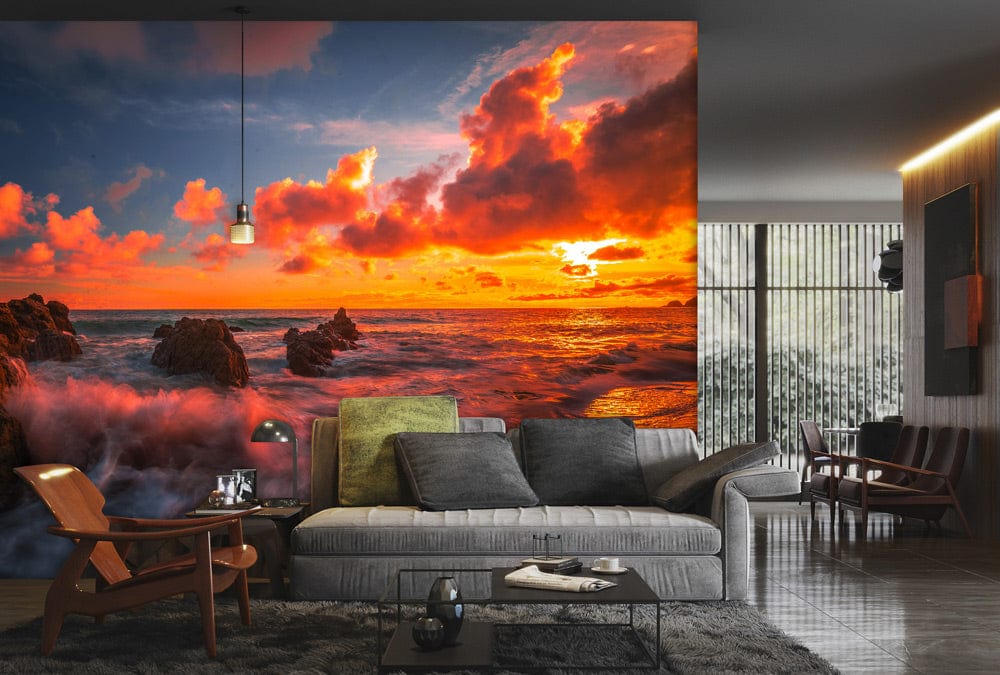 Vibrant Sunset Seascape Mural Wallpaper with dramatic waves, modern grey sofa, wooden chairs, and sleek flooring.