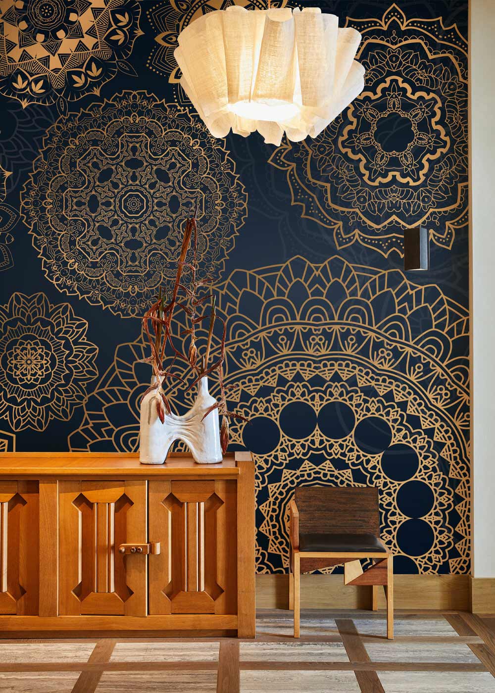 Elegant gold mandala dark blue wallpaper with wooden sideboard, chair, and modern ceiling light.