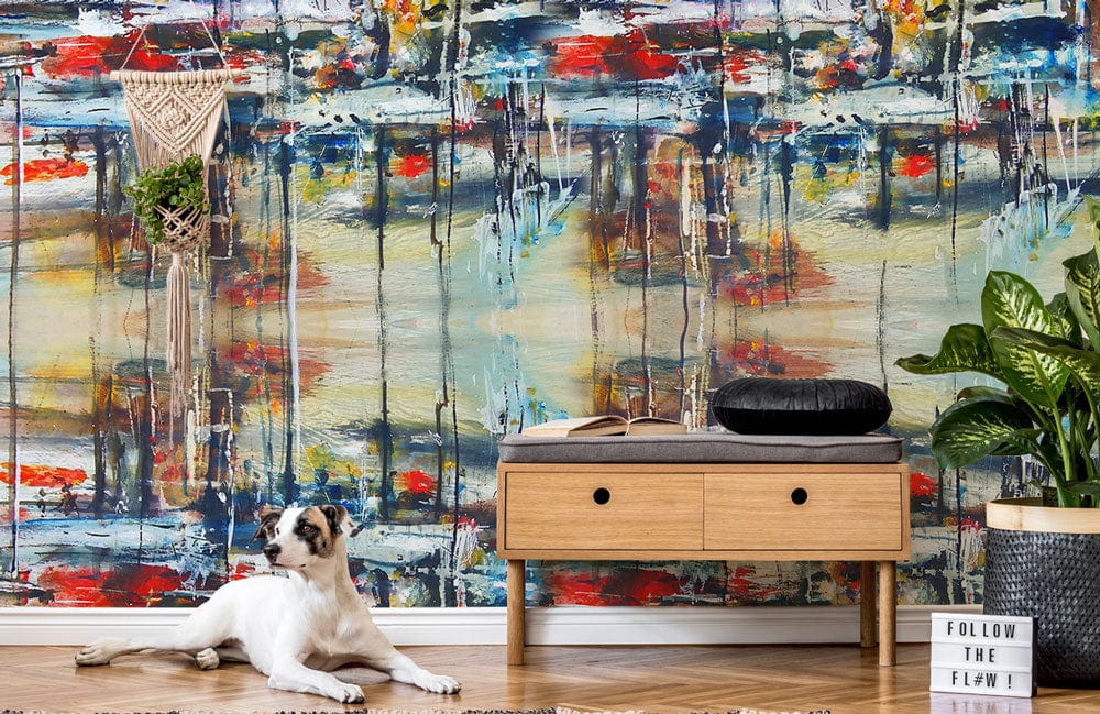 Vibrant abstract mural wallpaper with bold colours, wood console, dog, and rug in living room.