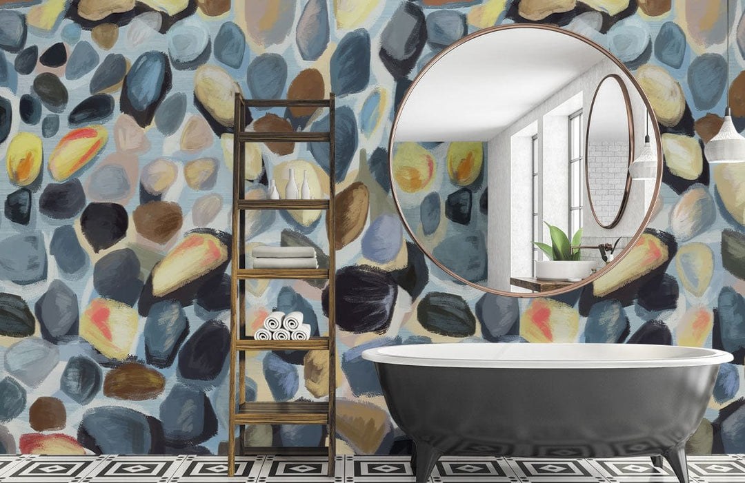 Multicoloured watercolour pebble mural wallpaper in bathroom with ladder shelving, black bathtub, patterned flooring.