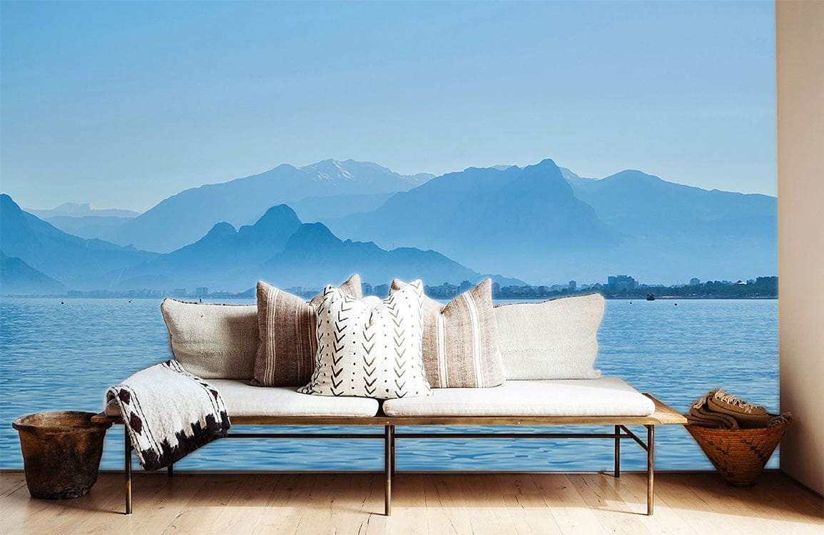 Tranquil Blue Mountain Sea Vista Mural, minimalist white sofa, wooden flooring, serene interior setting.