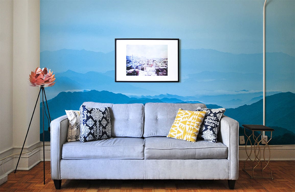 Serene Blue Mountain Mist Mural Wallpaper, grey sofa, wooden flooring, living room art, cosy ambience.