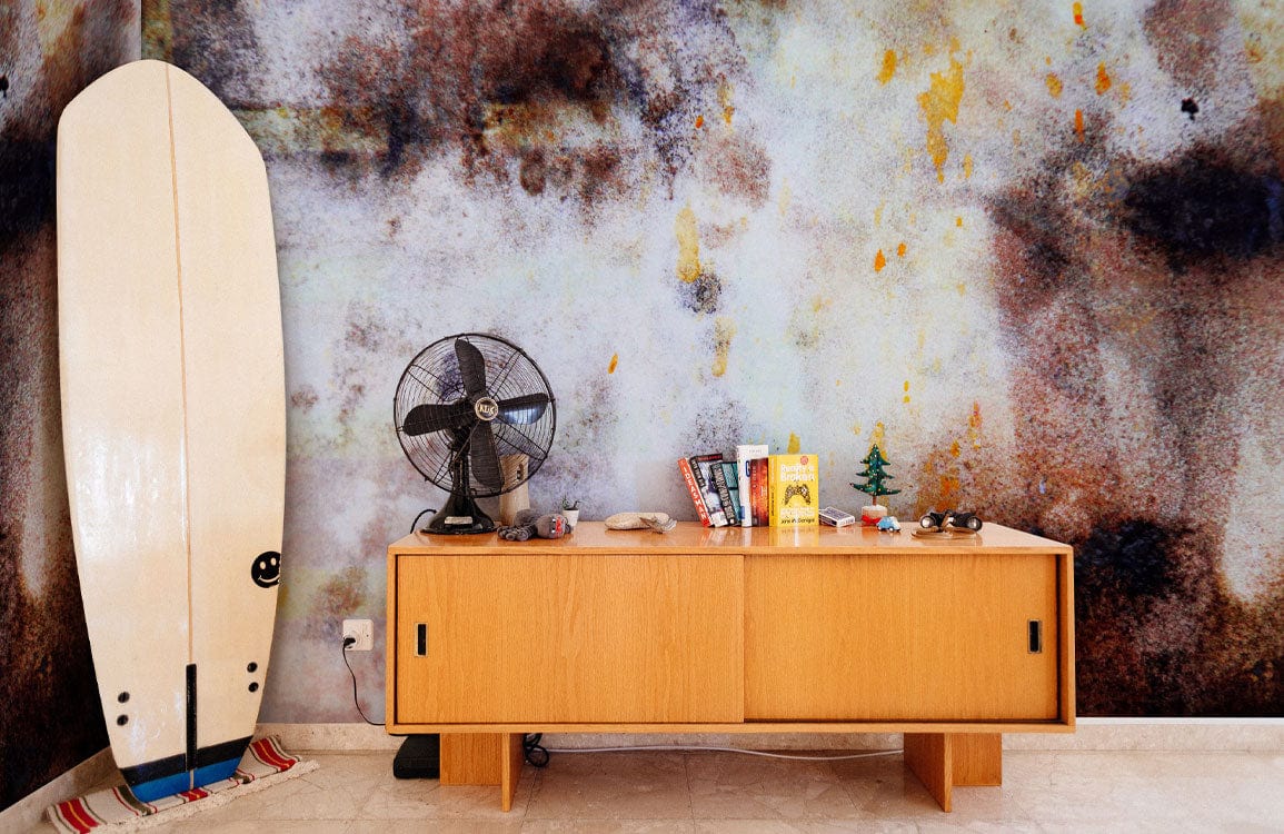 Abstract earthy tones wallpaper; rustic design with wooden sideboard, vintage fan, surfboard, and artistic mural.