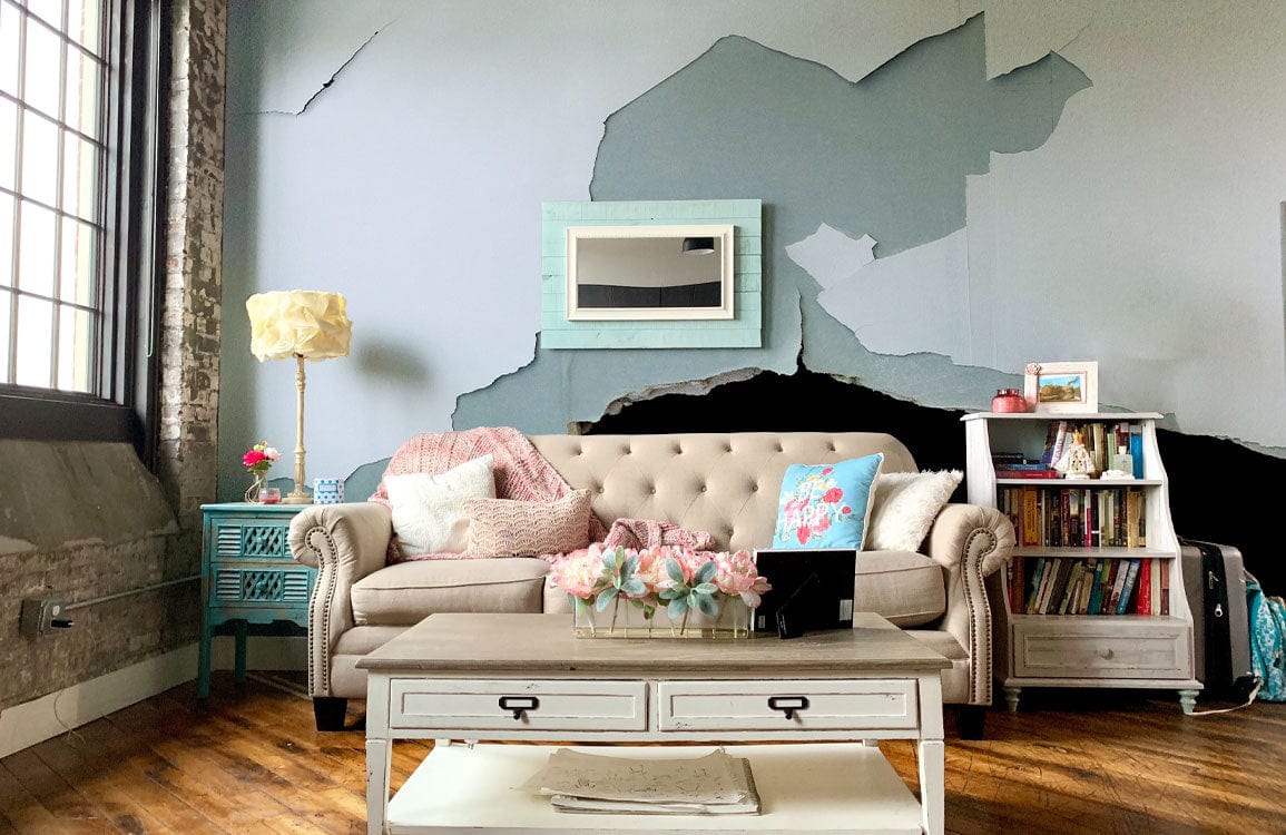 Vintage distressed blue and white rustic wallpaper with beige sofa, hardwood flooring, bright living room.