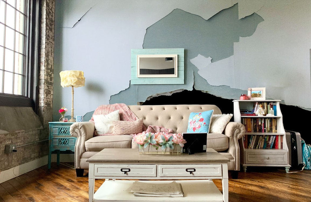 Vintage distressed blue and white rustic wallpaper with beige sofa, hardwood flooring, bright living room.
