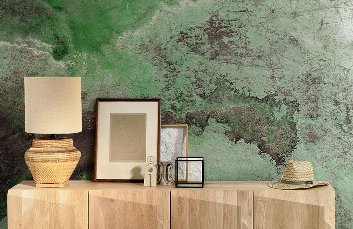 Emerald green and earthy brown abstract mural with wooden cabinet; lamp and hat decor accents.