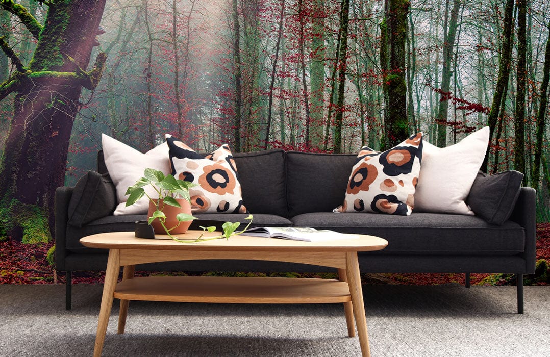 Mystical forest mural wallpaper; dark sofa; wooden table; grey carpet; living room decor.