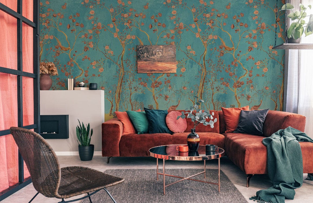 Elegant teal chinoiserie wallpaper with gold flora, velvet sofa, modern chair, lounge room setting.