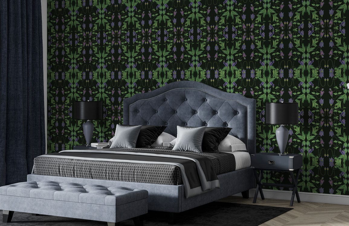Dark botanical wallpaper; vibrant green foliage; grey upholstered bed and ottoman; bedroom with dark lamps.
