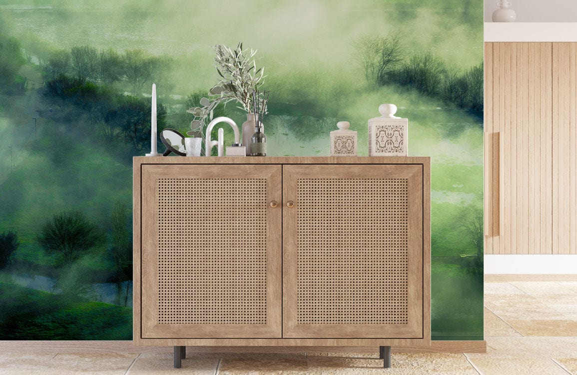 Serene Misty Landscape Green Mural Wallpaper with wooden sideboard; peaceful room setting; neutral flooring.