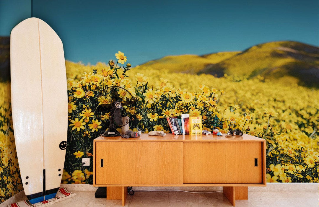 Golden Daisy Field Landscape Mural Wallpaper; vibrant nature Décor with surfboard, wooden sideboard, tiled flooring.