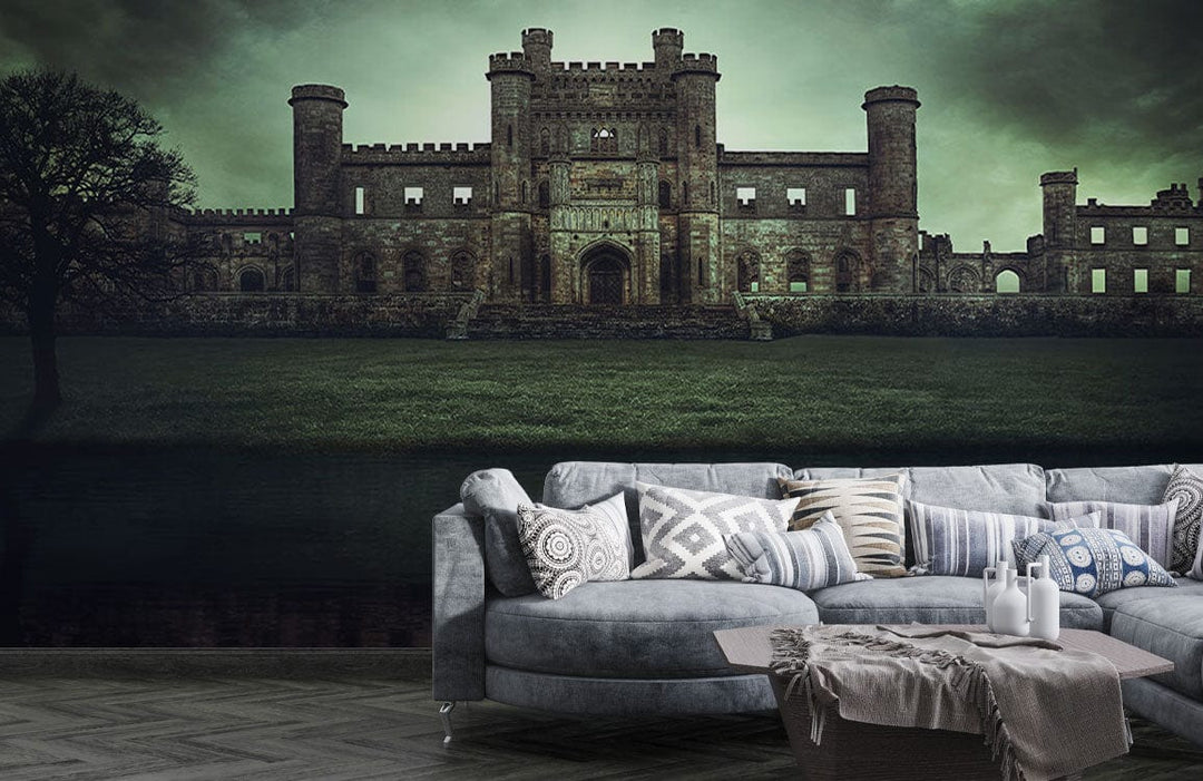 Gothic castle mural wallpaper in moody green, with grey sectional sofa on wood flooring in living room.