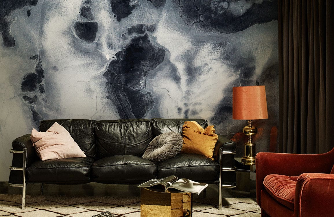 Abstract marble wallpaper with orange hues, black leather sofa, red armchair, patterned rug, living room.